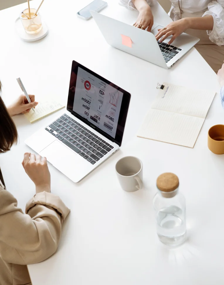 Dos mujeres con sus ordenadores en una mesa de reuniones
